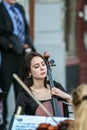 Cellist woman playing on the street, side view.