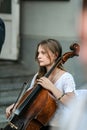 Cellist woman playing on the street, side view.