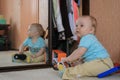 Cute baby boy sitting on the floor and playing shoes by the mirror. Royalty Free Stock Photo