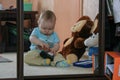 Cute baby boy sitting on the floor and playing shoes by the mirror. Royalty Free Stock Photo