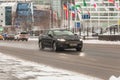 Black car Ford Mondeo MK5 driving on winter city road with dirty melt snow