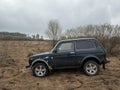 Black Russian off-road car Lada Niva 4x4 VAZ 2121 / 21214 parked on the field.