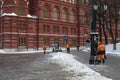 Moscow, Russia - December 28, 2021: Snow removal in front of the Historical Museum. Workers in orange vests remove snow