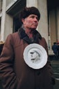 Senior man holds plate with portrait of Lenin