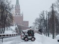 A small loader excavator bobcat removes snow from the sidewalk near the Kremlin walls during a heavy snowfall