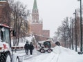 A small loader excavator bobcat removes snow from the sidewalk near the Kremlin walls during a heavy snowfall
