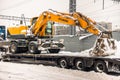 MOSCOW, RUSSIA - FEBRUARY 05, 2018: Specialised powerful lorry transports yellow wheel excavator Hyundai on a lowboy trailer.