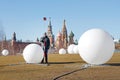 Technician with reflector for measuring distances by tachymeter on the background of white balls and St. Basil`s Cathedral