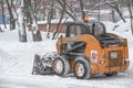 Moscow, Russia, February 13, 2021: Yellow tractor clears snow-covered roads on a city street Royalty Free Stock Photo