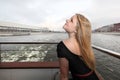 Beautiful blonde in profile and in a black dress on a ship in the city. Wind on the river Royalty Free Stock Photo