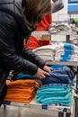 15.03.2020 Moscow, Russia. the girl chooses an orange t-shirt from a stack of t-shirts of different sizes stacked in the