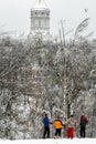 Group of adult people wearing colorful sportive clothers standing on background of forest and church. Skiing at winter park.