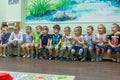 Group of children sitting on the bench in the kindergarten. Cute and funny kids in the room.
