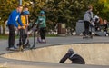 Group of teenager boys skateboarding and scooter riding in the park.