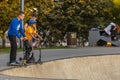 Group of teenager boys skateboarding and scooter riding in the park.