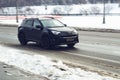 Urban winter landscape with snow drifts along the road. Fast moving black Toyota RAV4 car with motion blur effect