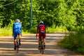 Cyclists train on a forest road with sports bikes. Athletic men in helmets ride a bicycle on the road. Back view on professional