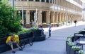 Moscow, Russia, July 2020: Man in a yellow t-shirt with bagpack on a bench with a phone, next to a Bicycle. People are walking Royalty Free Stock Photo