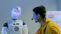 Funny humanoid robot with display face talking with guide man