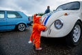 Moscow, Russia: July 06, 2019: A small child in a fox costume stands near a restored Volkswagen beetle and examines it with