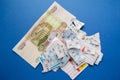 Moscow, Russia, July 2020: Torn lottery tickets with numbers with banknote of one hundred rubles on blue background. Russian Lotto