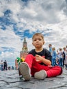 Moscow, Russia - July 7, 2018: unsatisfied, not happy boy sits on Red Square paving stones, tourist or political concept