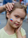 Moscow, Russia - July 7, 2018: young european girl with russian tricolor on cheek, patriotic face painting, fans bodyart