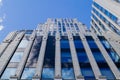 The blue sky with clouds is reflected in the glass of identical windows of modern office building