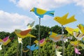 Colourful weather vanes in form of birds against trees and a blue sky with clouds at the city