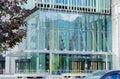 Moscow, Russia, June 2020: Glass entrance to a modern office building, a tree nearby, blurred cars passing by Royalty Free Stock Photo