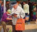 Standing middle-aged man reading a book near the tent with books at the Book Fair