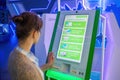 Woman using interactive touchscreen green kiosk at modern museum or exhibition