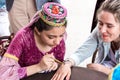 The girl master puts a temporary henna tattoo on the hand of a young woman