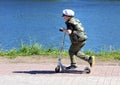 A little boy is riding a scooter along the embankment. Children playing in the park.