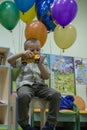 Little boy sitting on the chair on background of colorful balloons.