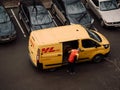 Moscow, Russia - March 11, 2020: DHL Deutsche Post courier in yellow-red uniform near minivan with company logos. DHL