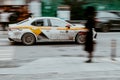 Dirty white Yandex taxi on the Moscow streets in motion. Fast moving taxi car on the autumn urban road