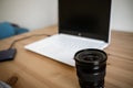 A DSLR lens on a wooden table together with a photo camera, computer Royalty Free Stock Photo