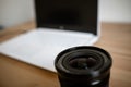 A DSLR lens on a wooden table together with a photo camera, computer Royalty Free Stock Photo