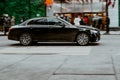 Mercedes-Benz C-class rides on the city road. Shiny black sedan car in motion. Urban scene with riding vehicle and blurred