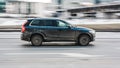 Volvo XC90 SUV in motion on the city road. Side view of black dirty crossover driving in the street