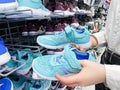 Someone chooses childrens or womens blue sneakers in the sports goods store Decathlon