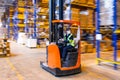 MOSCOW, RUSSIA - MARCH 18, 2021 Warehouse worker driving a forklift truck between high blue yellow steel shelves inside warehouse