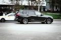 Fast moving black BMW X7 M50d on highway road. Overspeed in city concept. SUV car on city street in motion, side view