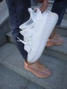 a girl in jeans and cream Adidas Yeezy boost 350 V2 `lundmark`and white Adidas Yeezy in hand
