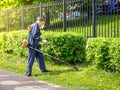 Man in overalls mows green grass with a gasoline lawn mower. Moscow, Russia - May 15, 2019