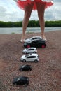 Moscow, Russia - May 03, 2019: Many toy Volkswagen Golf stand on the beach. They are lined up at the feet of a girl who holds