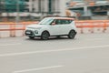 Side view of Kia Soul car in motion. White compact hatchback moving on the street