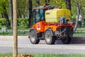 Moscow, Russia - May 01, 2019: Small orange sprinkler truck with plastic water tank riding on road sidewalk in sunny spring