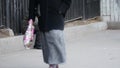 Pauper elderly man in winter coat sits on street with a disposable cup in hands